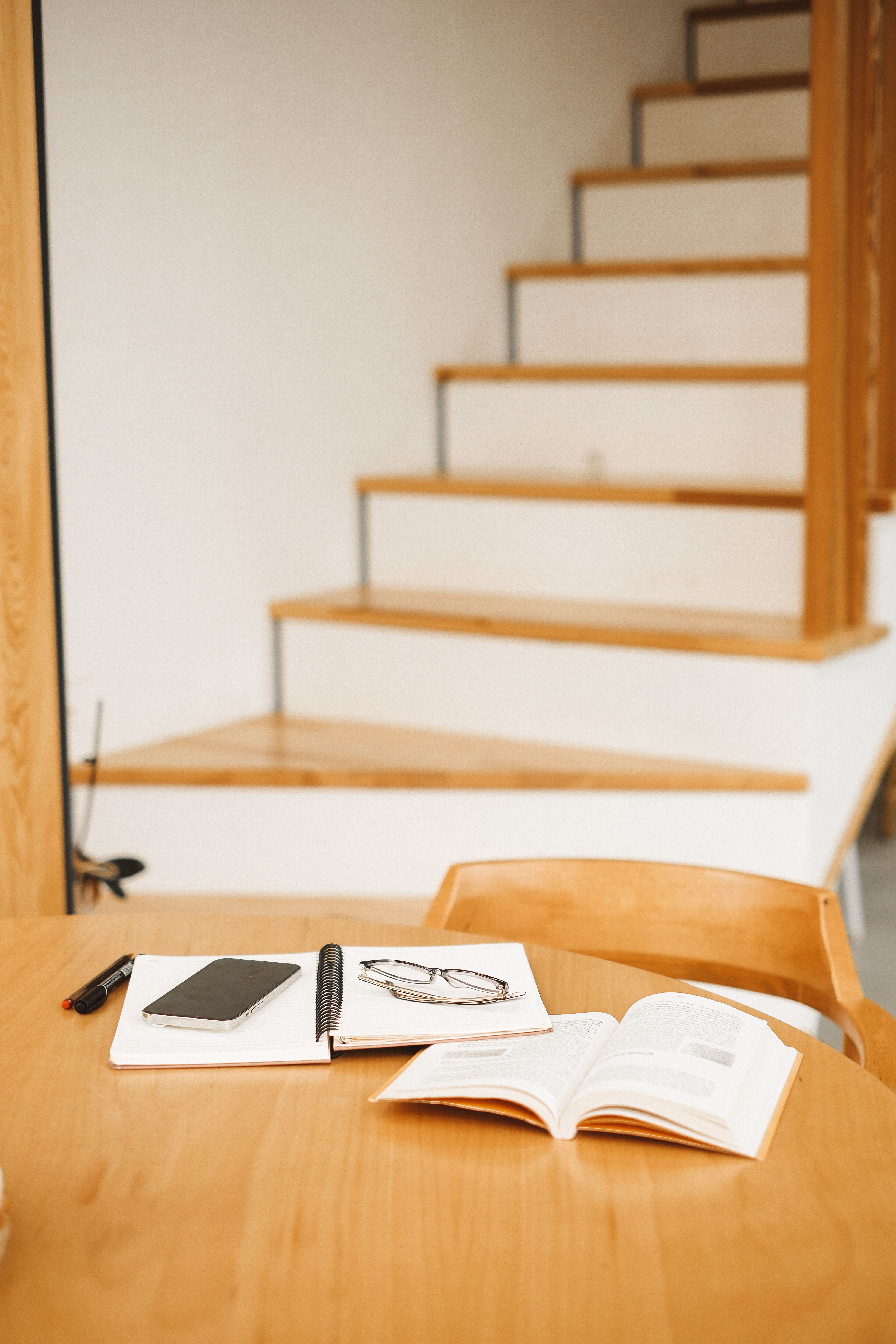 hand reaching for a phone resting on a wooden table next to a notebook