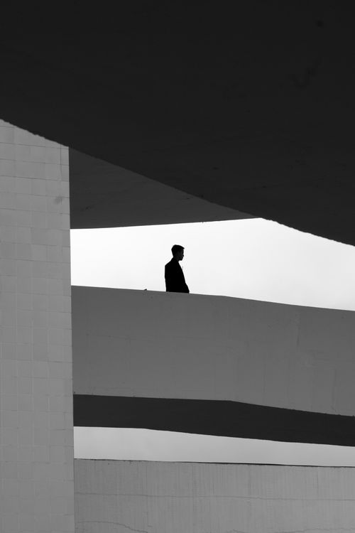 Free Black and white silhouette of a man amidst modern architecture, evoking minimalism and solitude. Stock Photo