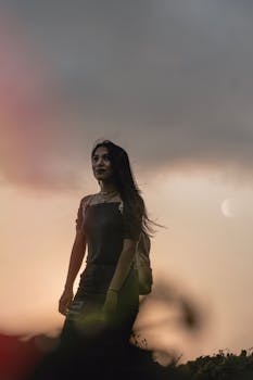 日落时分，一位年轻女子优雅地站在户外，散发着风格与魅力