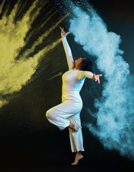 A captivating shot of a ballerina in motion with colorful smoke enhancing the dramatic effect.