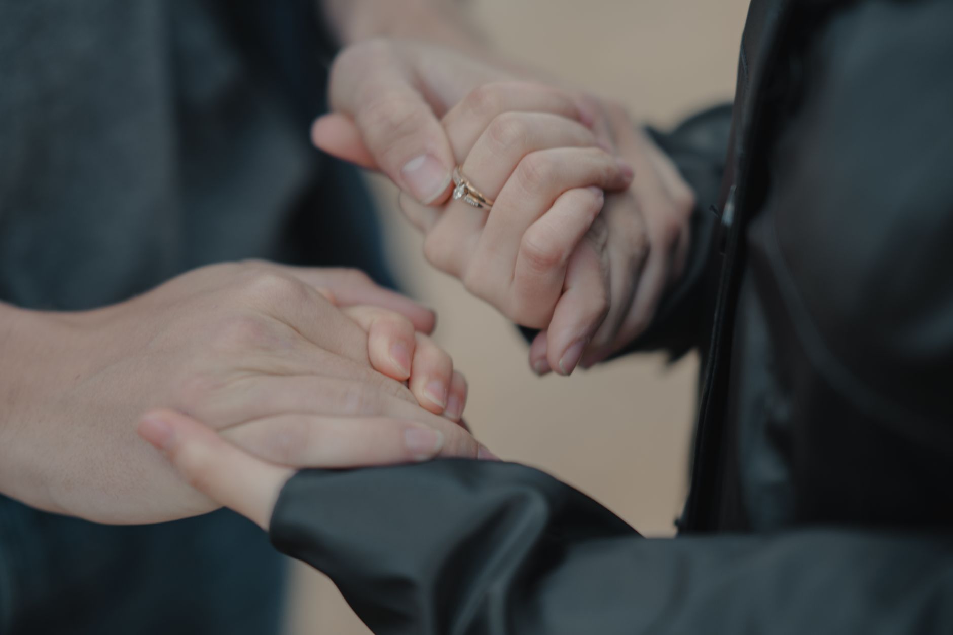 Intimate close-up of a couple holding hands, highlighting a ring, symbolizing love and commitment.