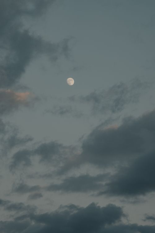 Free A serene night sky featuring the moon surrounded by clouds, creating a moody atmosphere. Stock Photo