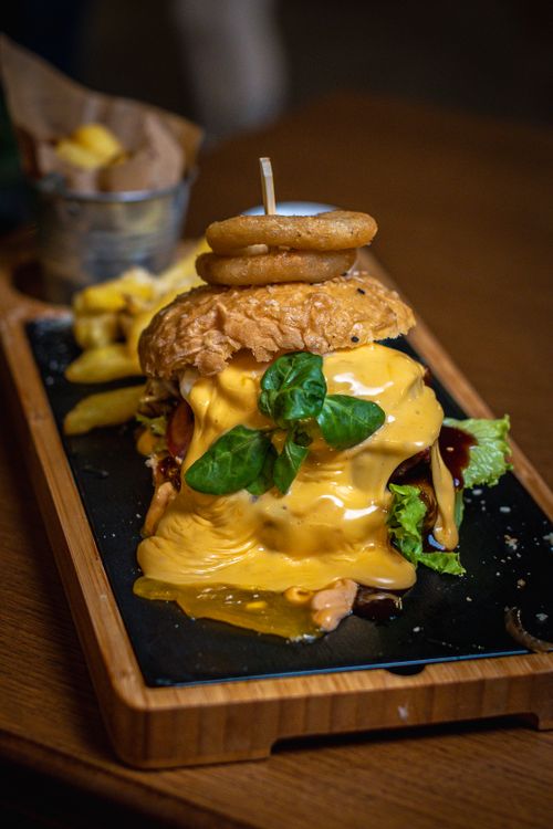 Free Delicious cheeseburger topped with onion rings, served with fries on a wooden tray. Stock Photo