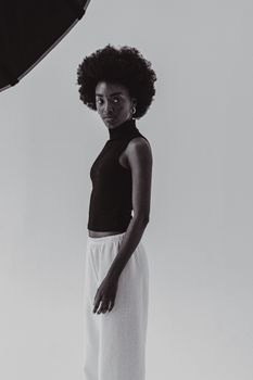 Elegant portrait of an African woman with afro hair wearing a black top in a studio setting.