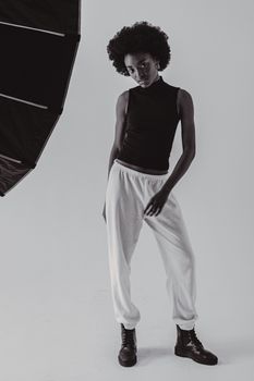Black and white photo of an African woman posing stylishly in a studio setting.