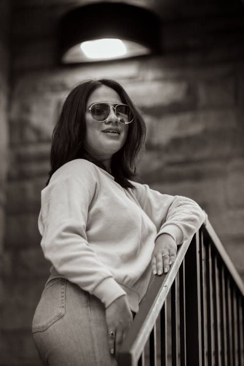 A woman in sunglasses and a sweater standing on a stair