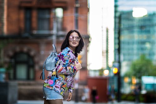 A woman in a colorful shirt and shorts walking down the street