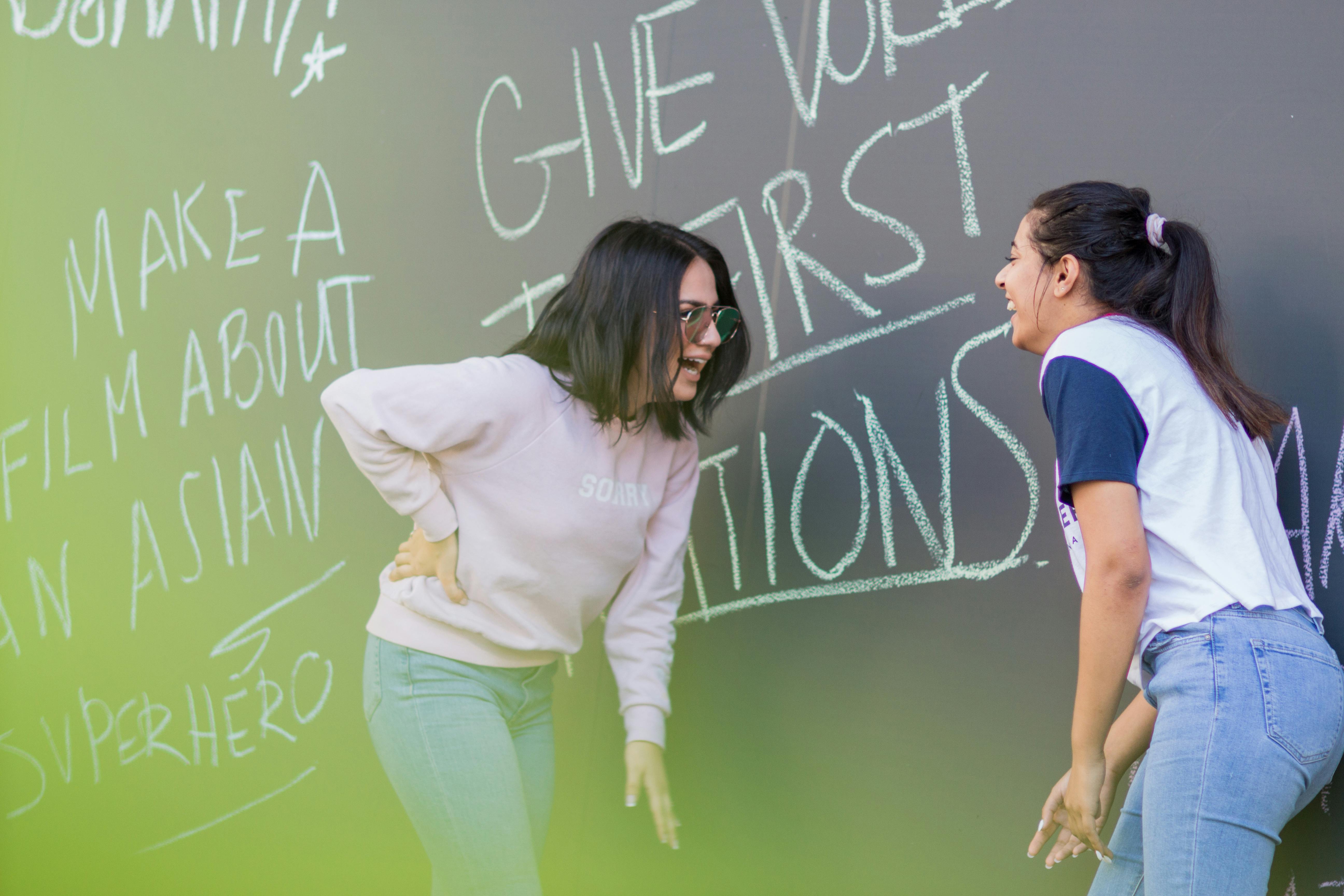 two women standing next to a chalkboard with the words give value give asian