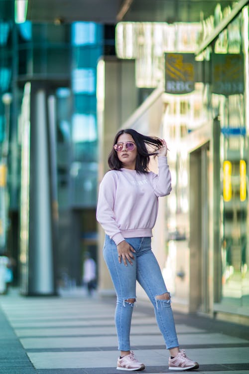 A woman in pink sweater and jeans standing on a city street
