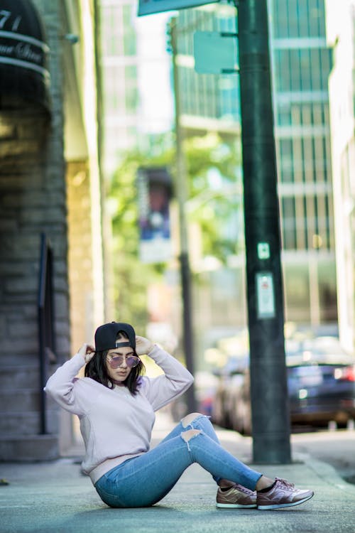 A woman sitting on the ground in front of a building