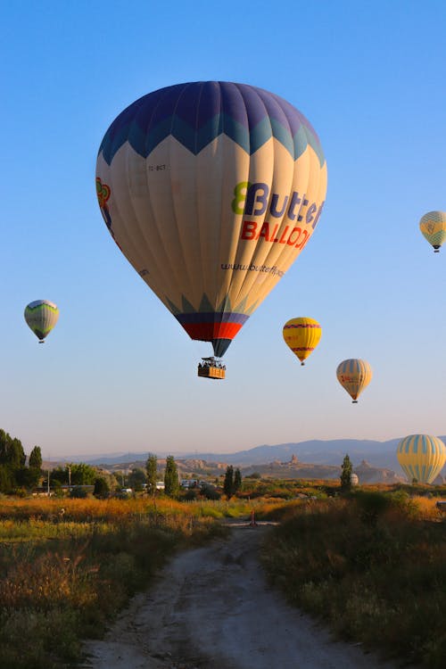 Hot Air Balloons Flying over Dirt Road in Countryside