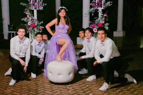 A Girl in a Prom Dress Standing in the Middle of a Group of Boys 