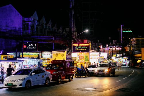 Free Bustling night scene on a lively street in Bangkok, lit by neon signs and crowded with traffic. Stock Photo