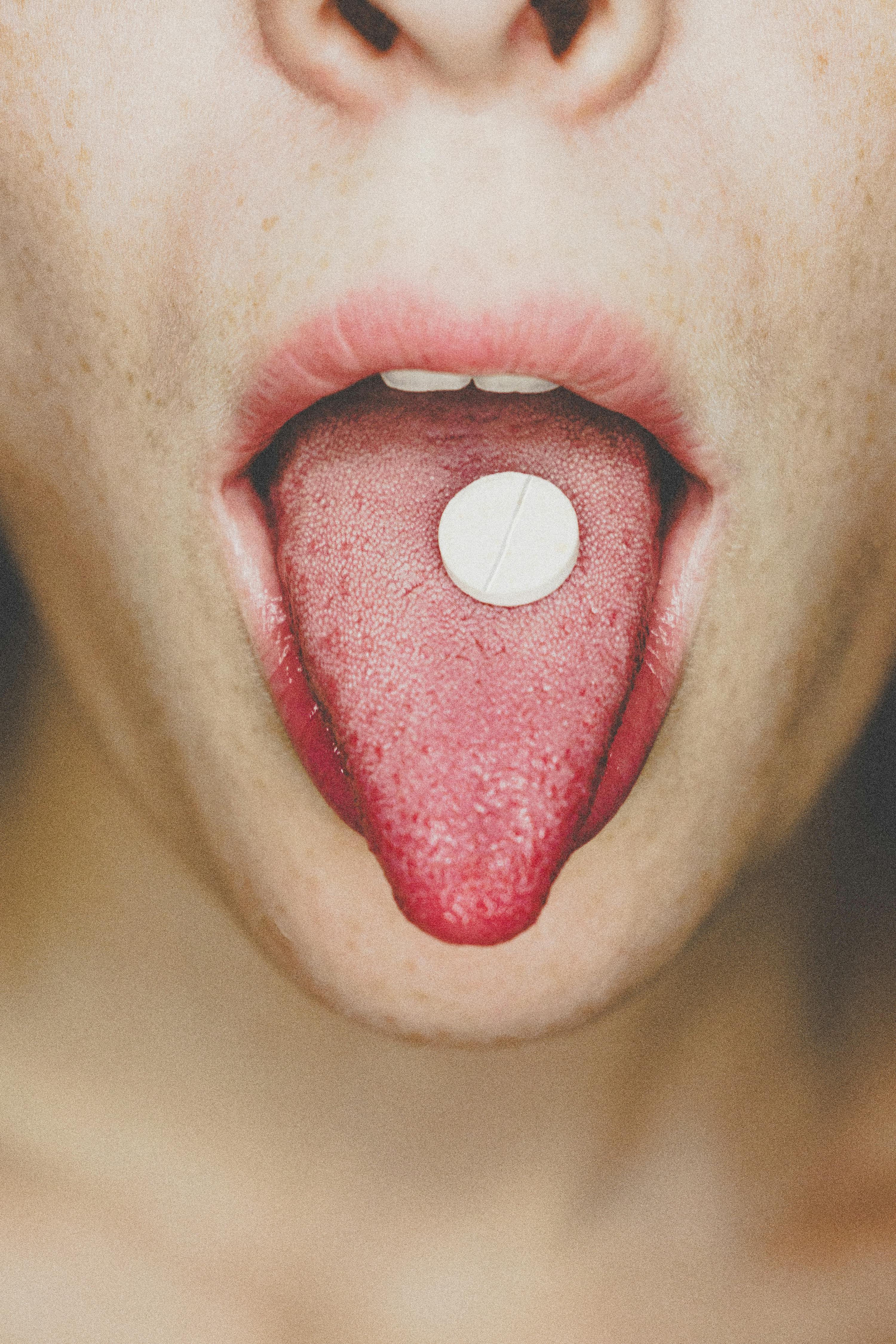 Close-up photo of a pill on a tongue, symbolizing medical themes.