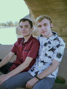 A happy couple sitting outdoors under bridge on a sunny day.