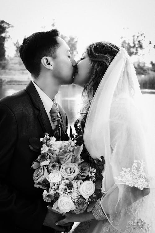 Kissing Newlyweds with a Bouquet of Flowers