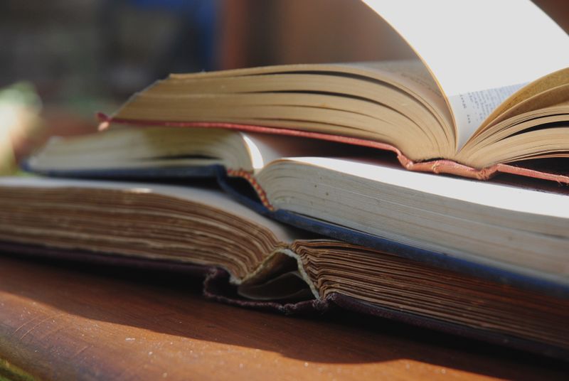 Stack of open books on a wooden table