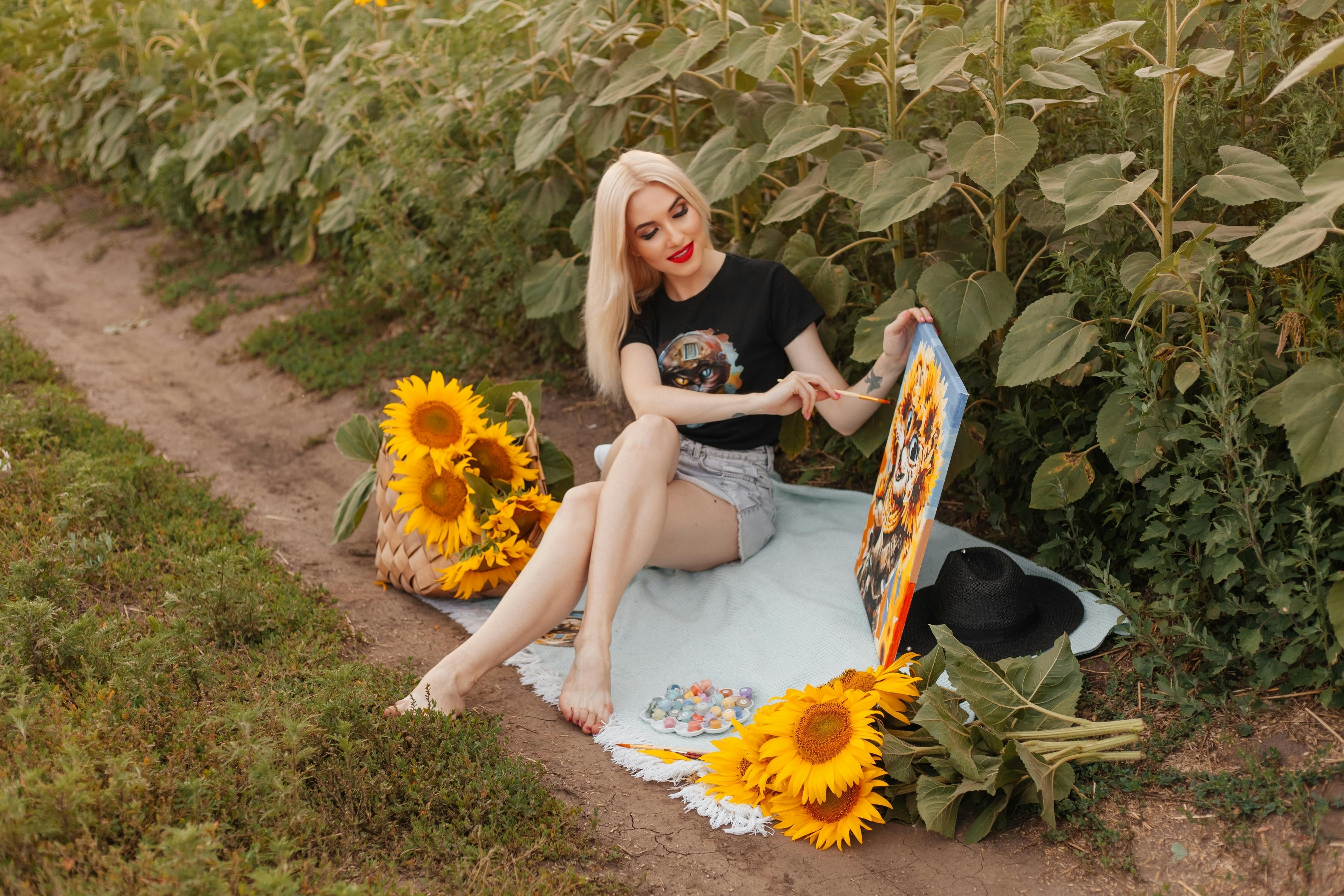 a woman sitting on the ground in a field with sunflowers