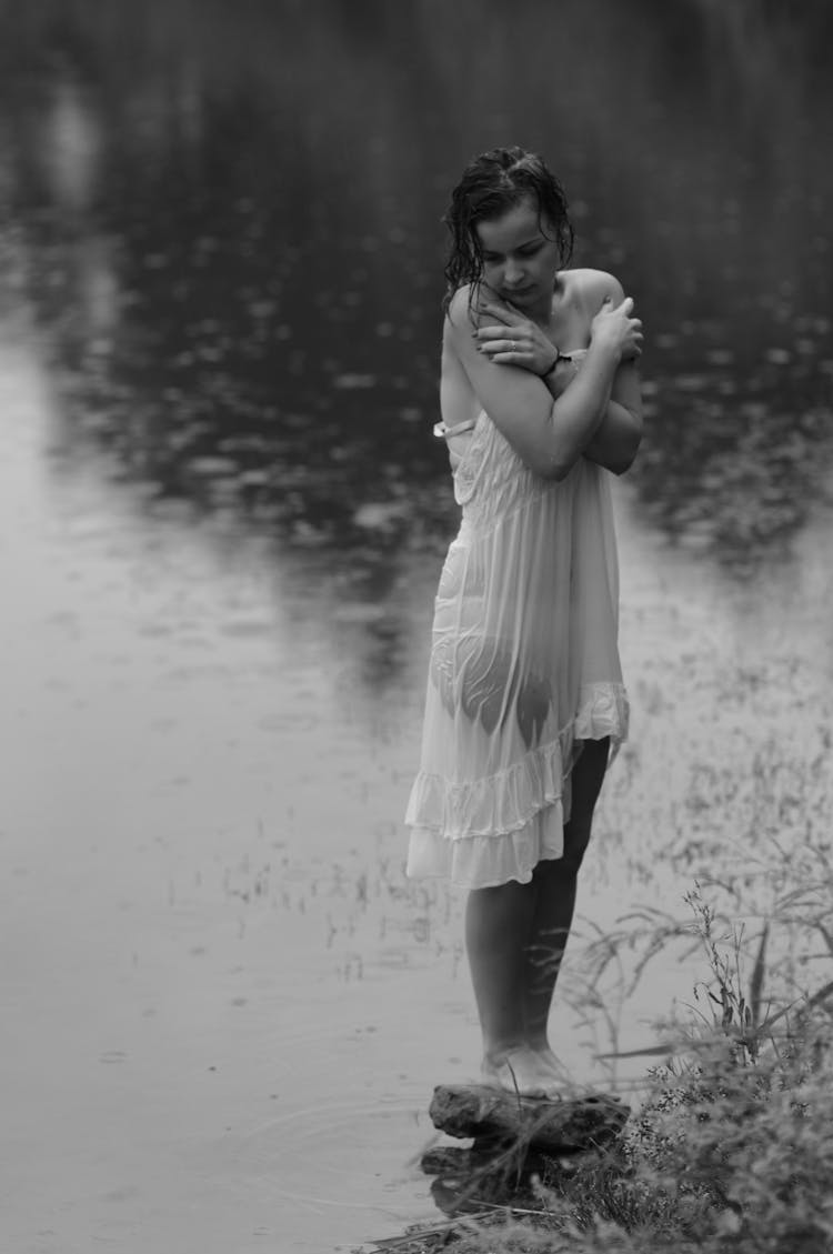 Woman In A Wet White Dress Standing On A Rock On The Shore 