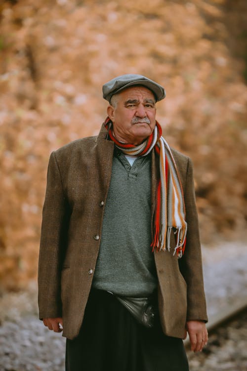 Elderly Man Wearing a Hat and Scarf Standing Outside 