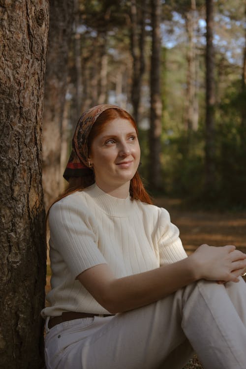 A woman sitting in the woods with her hair in a bun