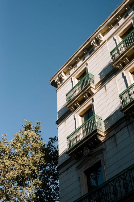 A classic residential building facade with green balconies under clear blue skies.