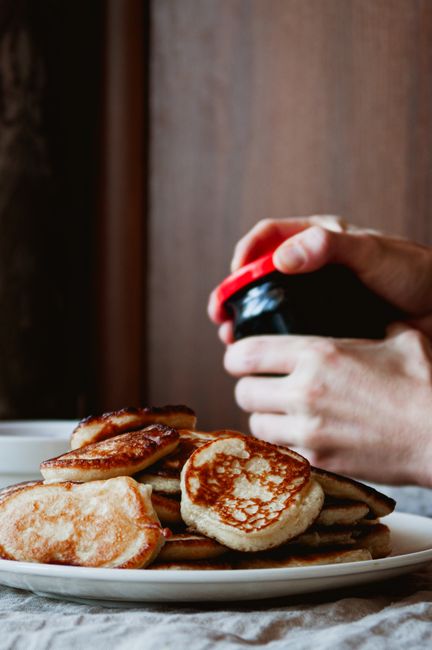 Close-up of Polish-style pancakes with a person opening a jar of jam.