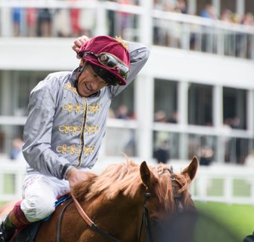 Jockey celebrating victory at Ascot Racecourse, England on a thoroughbred horse.