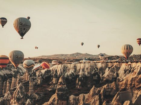 Scenic view of hot air balloons soaring over rock formations in Cappadocia at sunrise.
