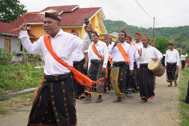 Warga dalam pakaian adat berparade di jalan desa saat perayaan budaya