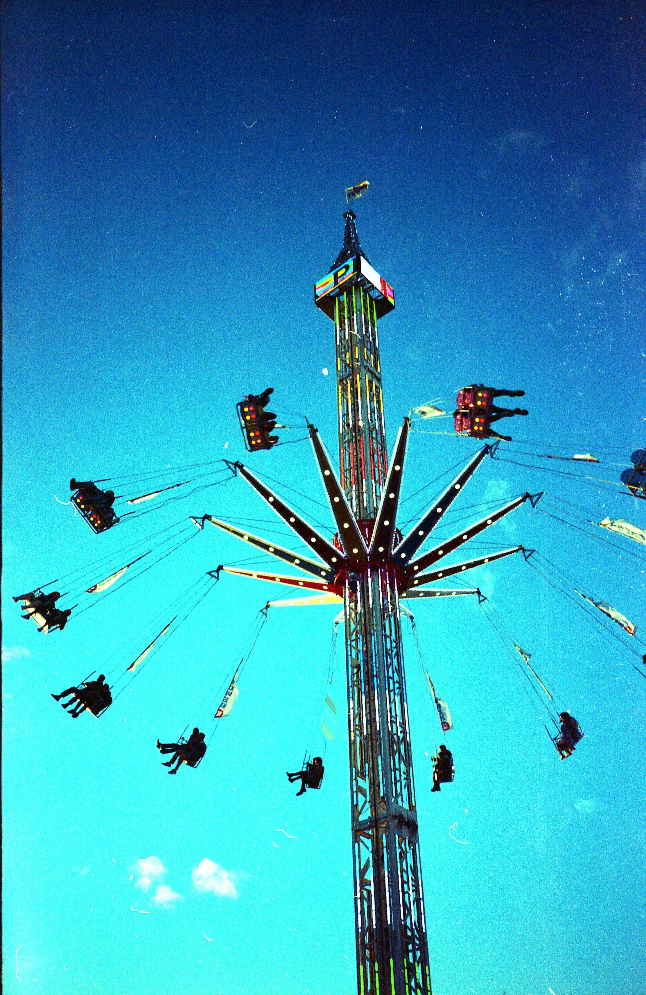 A vibrant carousel ride in Legnano, Italy against a clear blue sky.