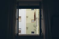 A view of an urban apartment building facade framed by an open window.