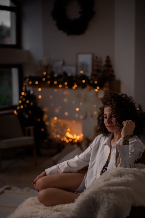 Woman Sitting in a Room with Christmas Lights and Decorations 