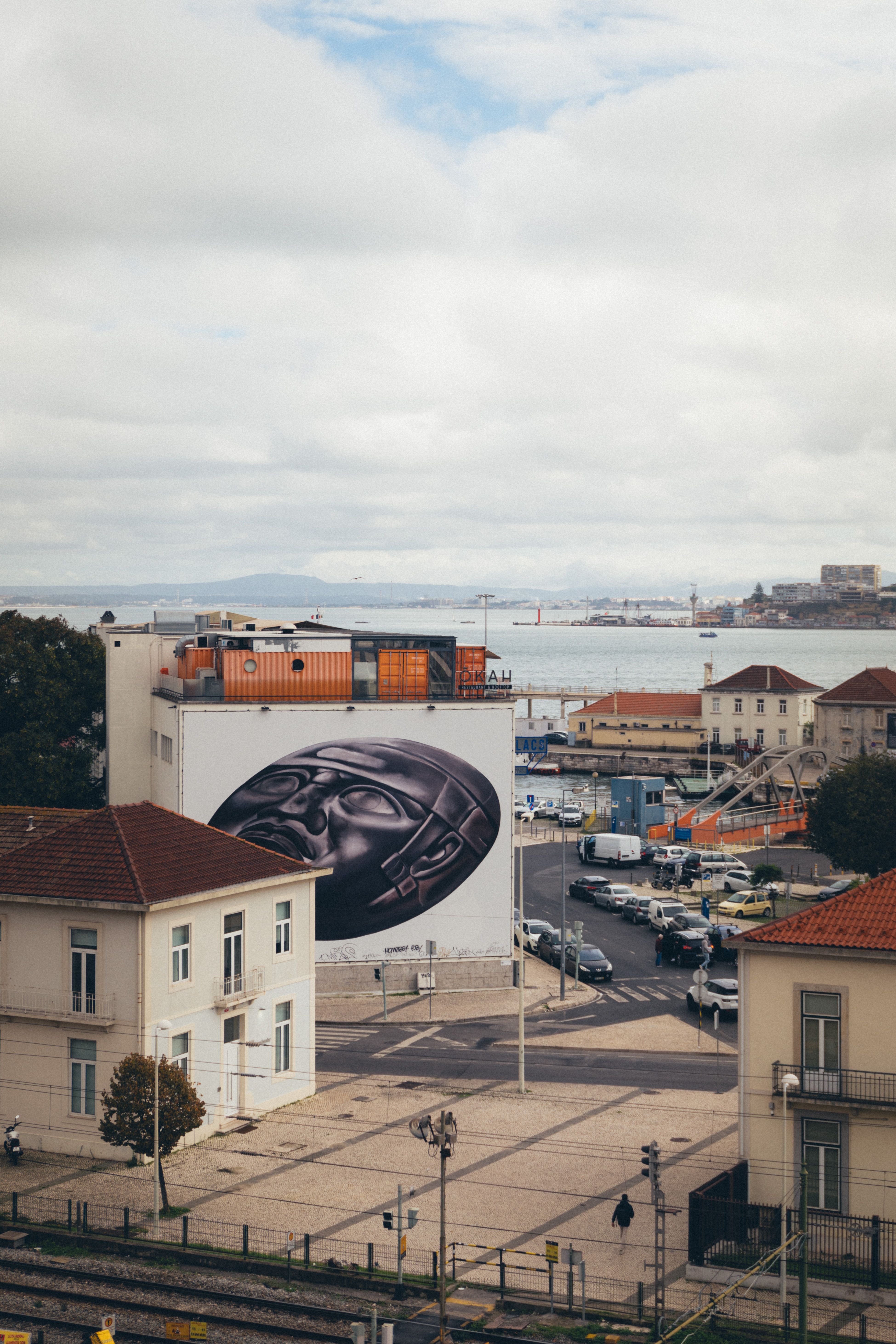 A captivating view of a large street art mural against Lisbon's waterfront backdrop.
