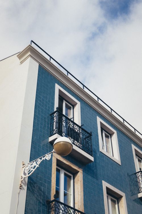 Free Low angle view of a blue-tiled building exterior with ornate balconies against a cloudy sky. Stock Photo