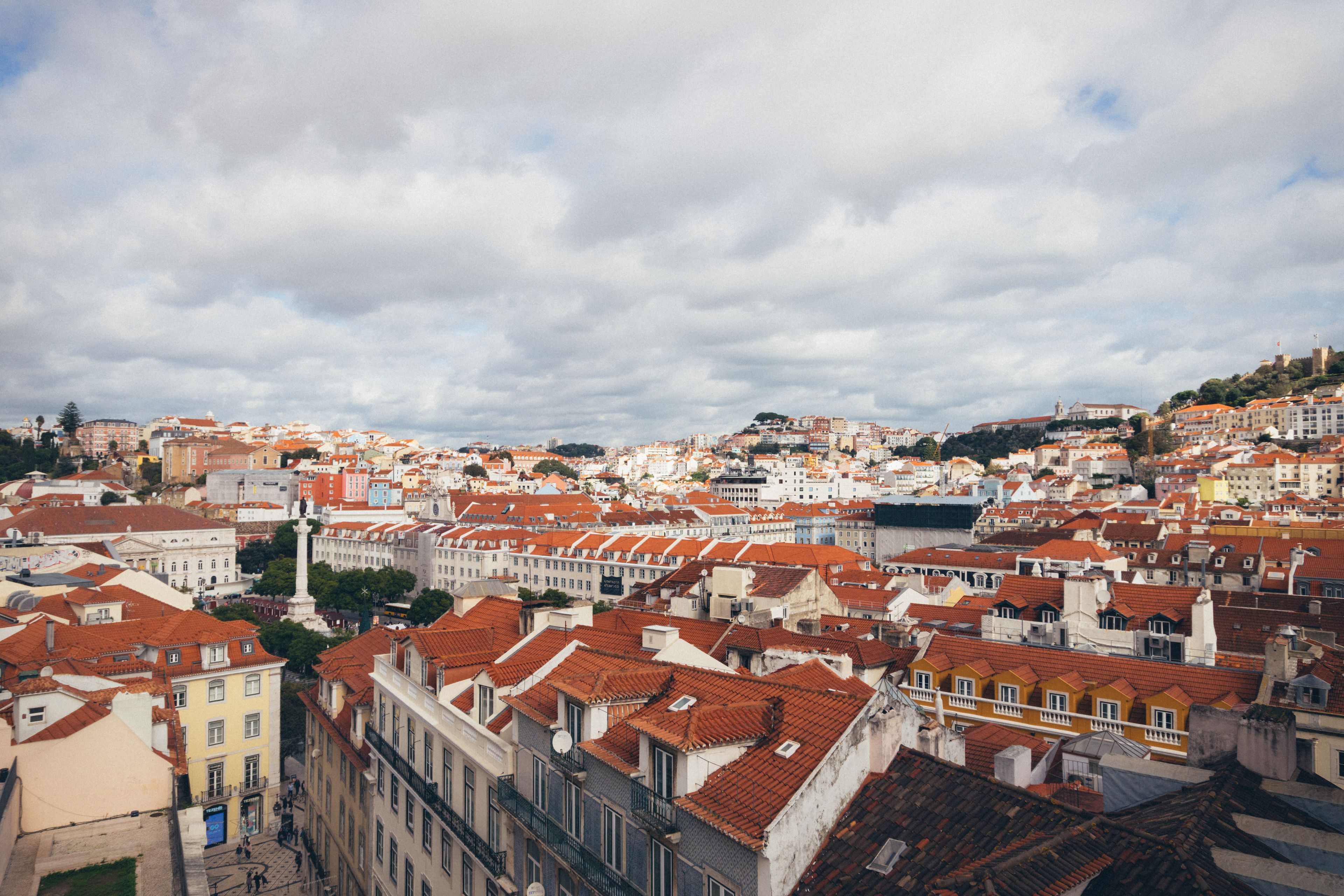 A picturesque aerial view of Lisbon, showcasing its iconic red rooftops and historic architecture on a cloudy day.