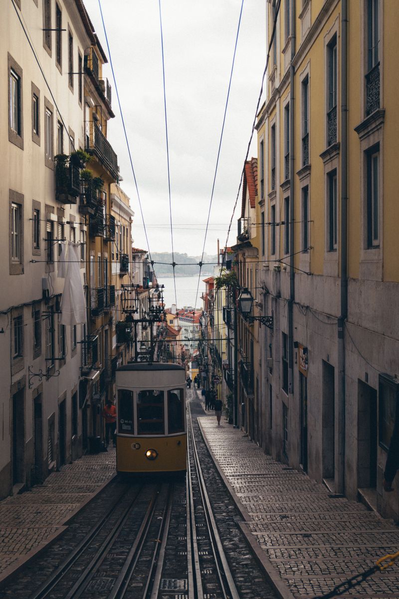 People and Trams in Narrow Alley in Lisbon, Portugal · Free Stock Photo
