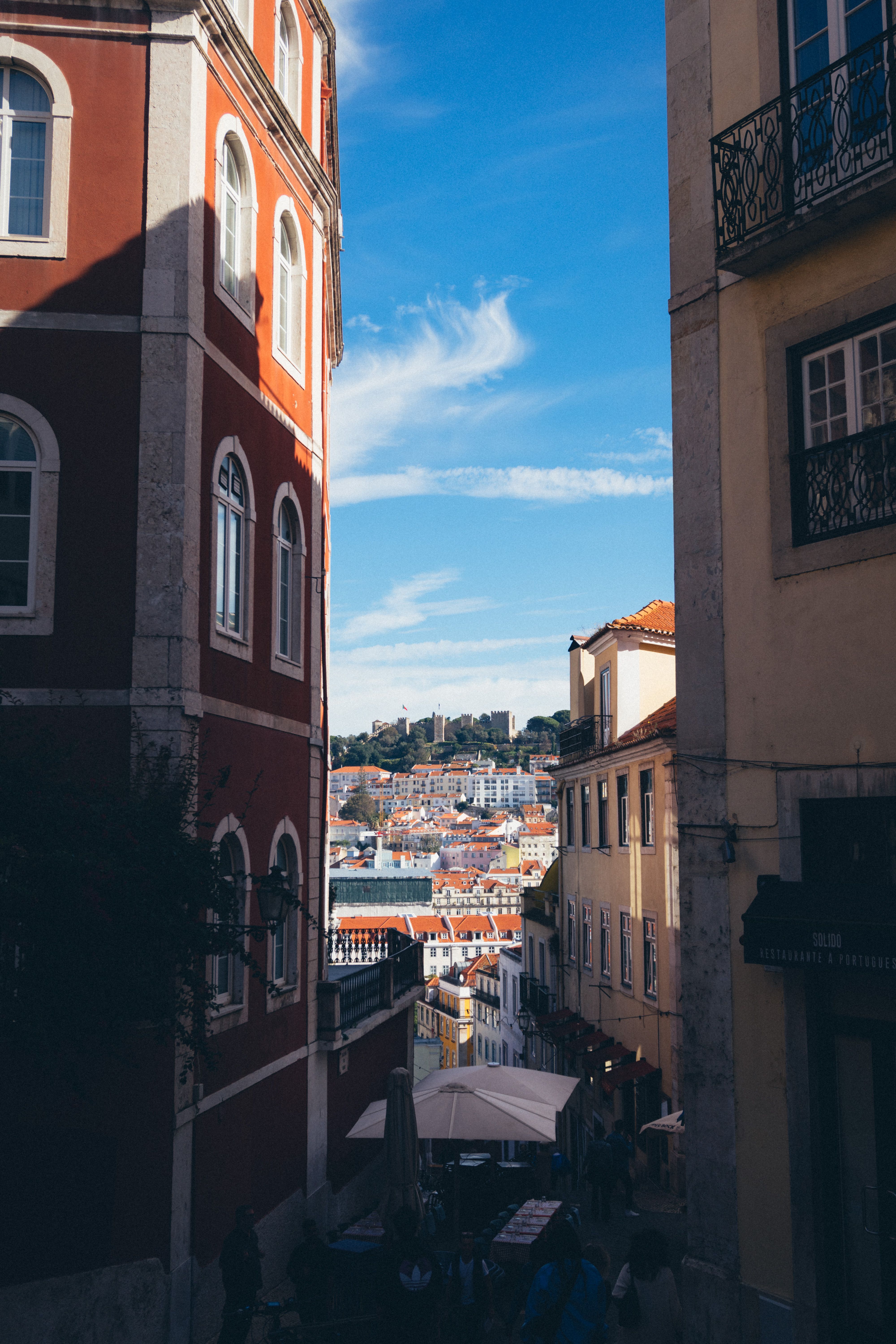 Charming view of historic Lisbon architecture through a narrow alleyway featuring vibrant buildings.