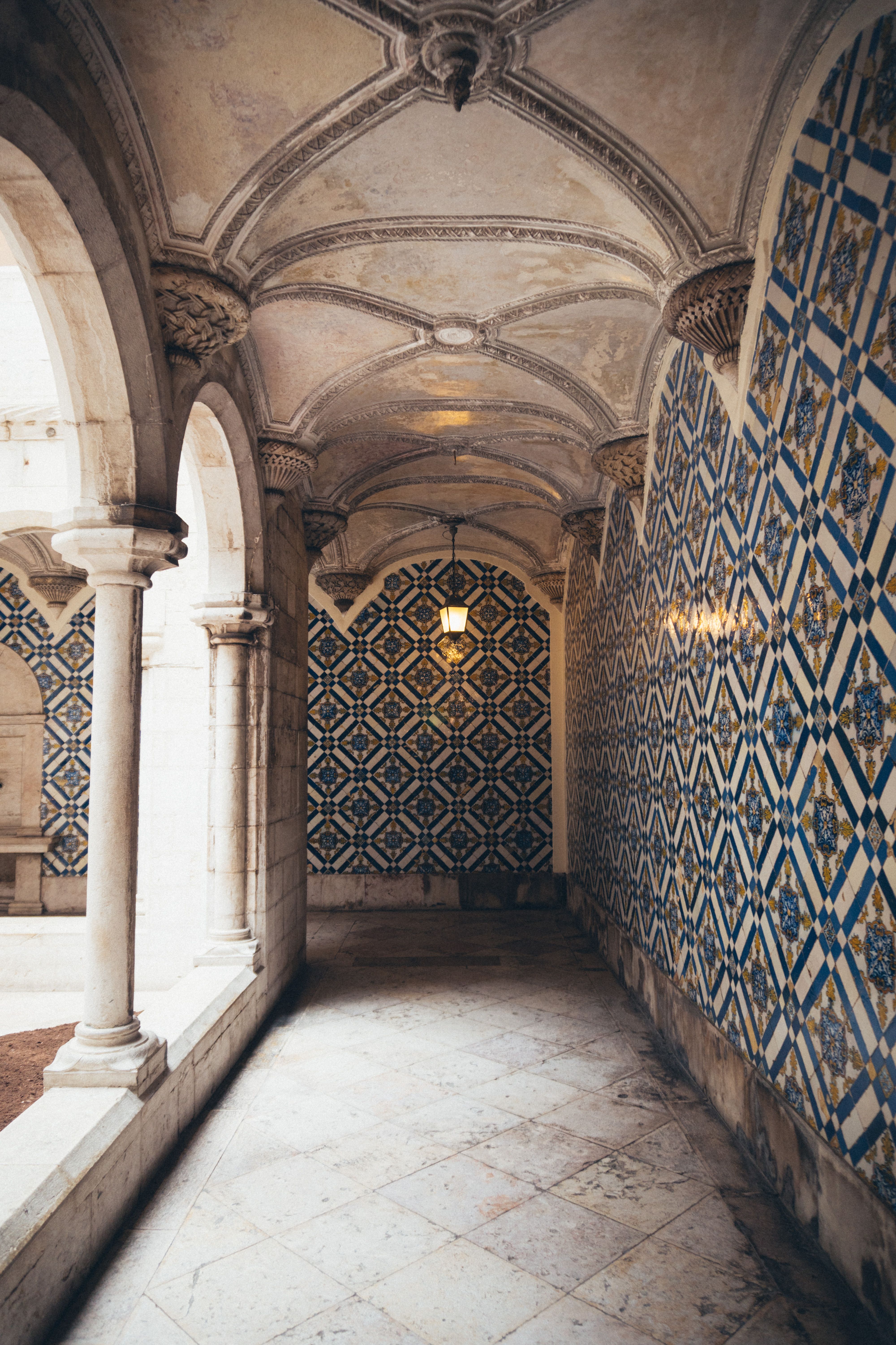 Discover intricate tile work within a historic cloister, showcasing Gothic architecture.