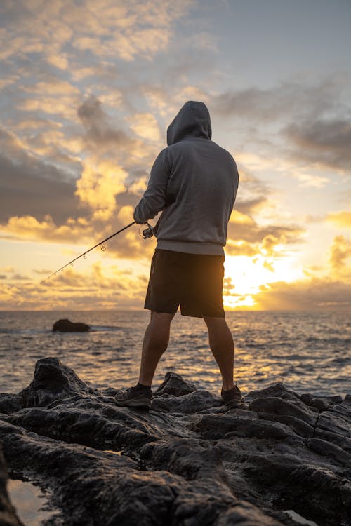 Back View of a Man Fishing in the Sea at Sunset 