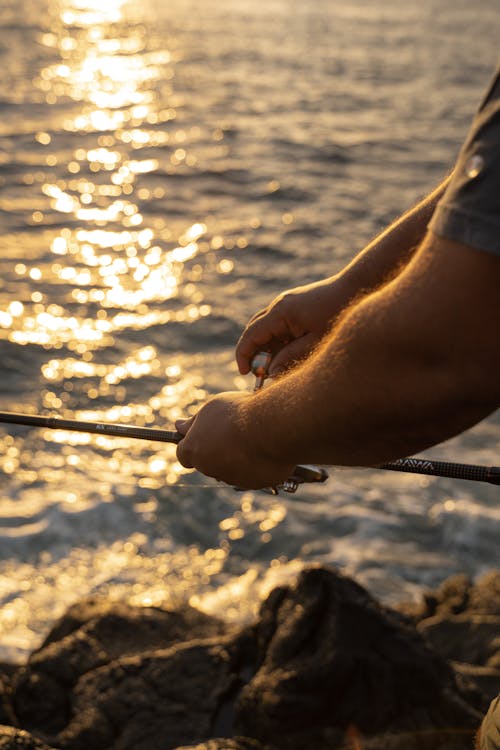 Close-up of an Angler Hands Reeling In the Line of the Fishing Rod