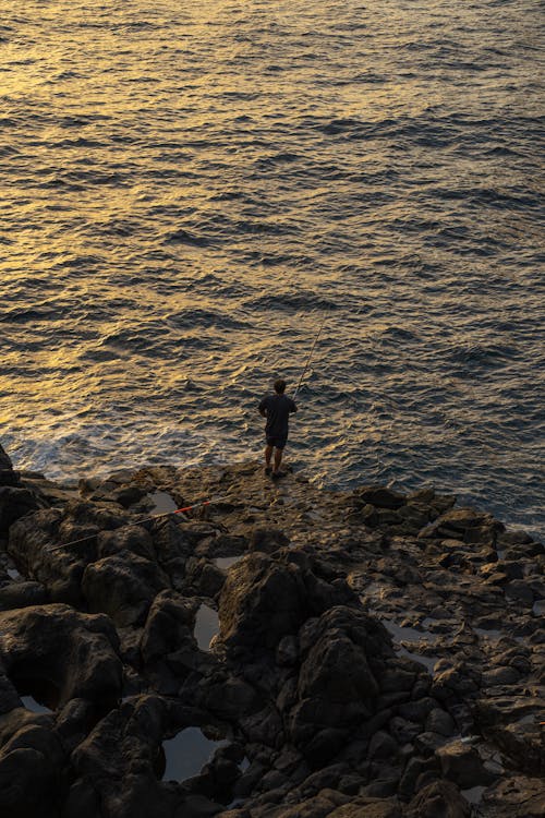 Aerial View of a Man Fishing in the Sea at Sunset