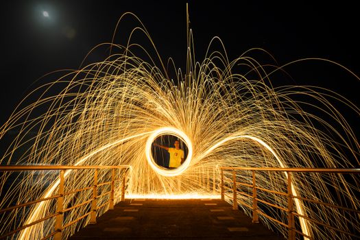 A captivating steel wool spinning performance captured at night on a pier.