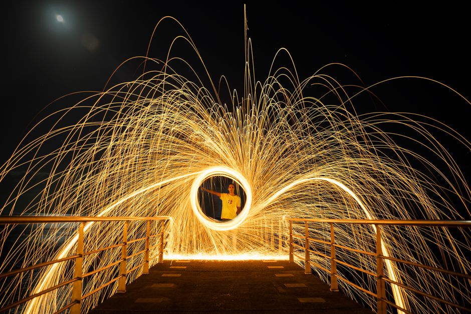 A captivating steel wool spinning performance captured at night on a pier.