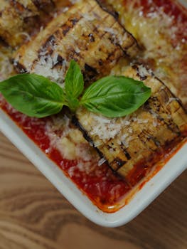 Close-up of delicious baked eggplant parmesan garnished with fresh basil leaves.