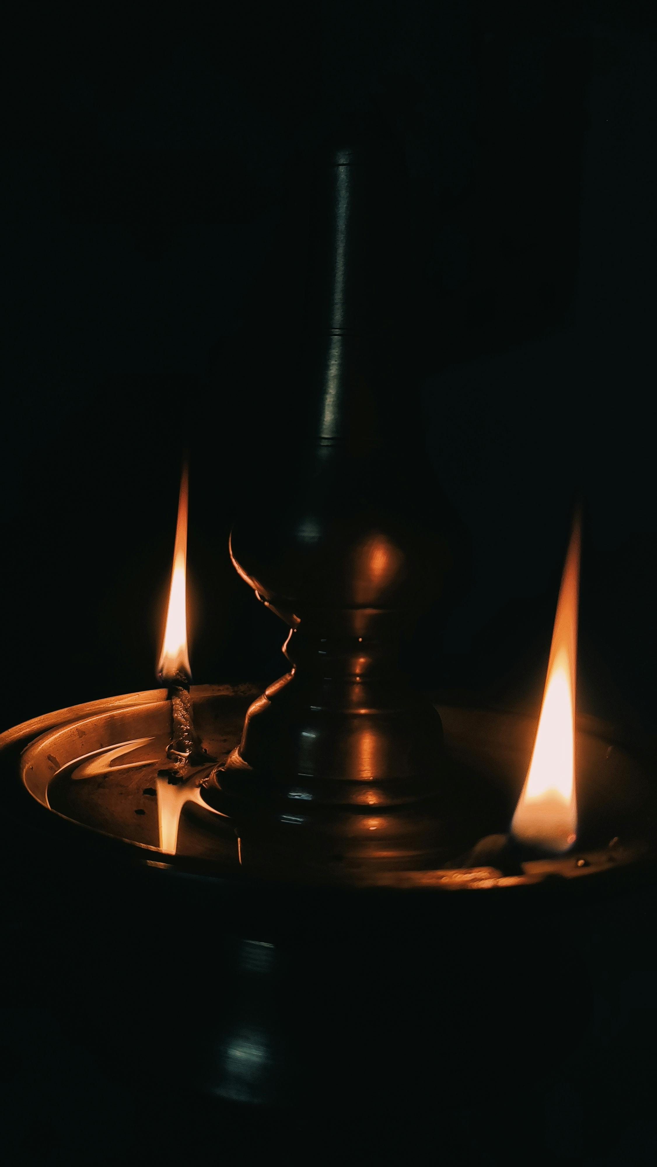 Artistic capture of a glowing brass oil lamp with warm candle flames, creating a serene ambiance.