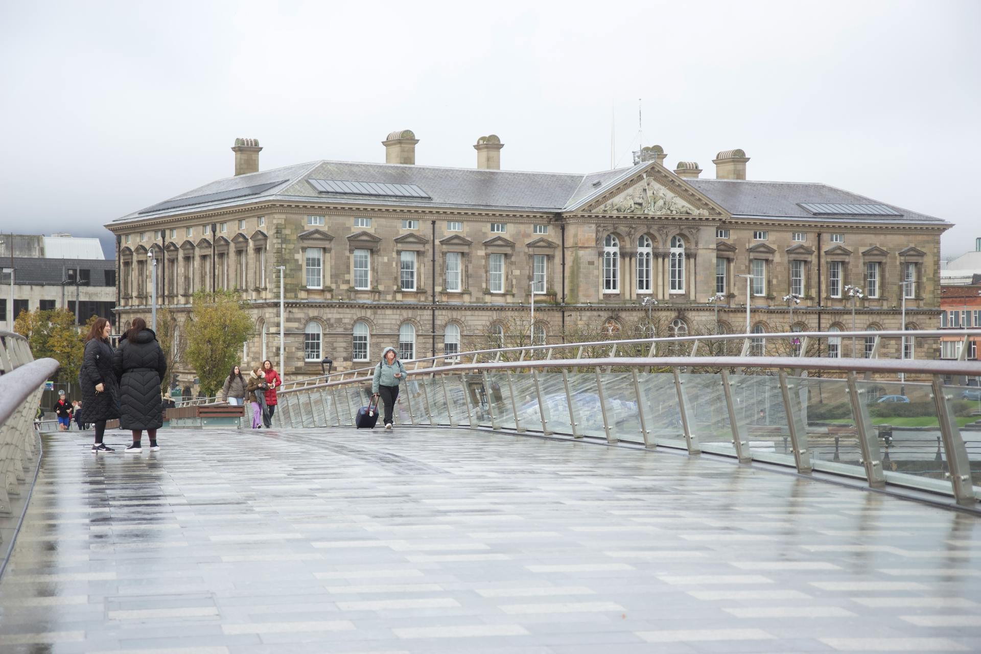 Scenic view of a pedestrian bridge in Belfast with a historic building in the background.