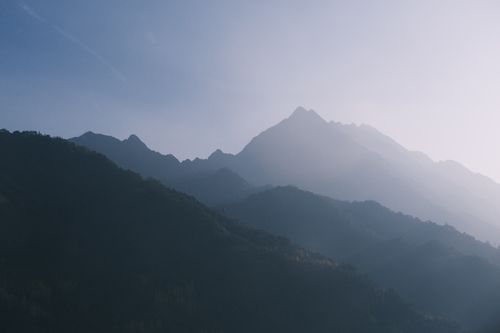 Free Beautiful backlit mountain silhouettes in a serene dawn landscape with mist and sunlight. Stock Photo