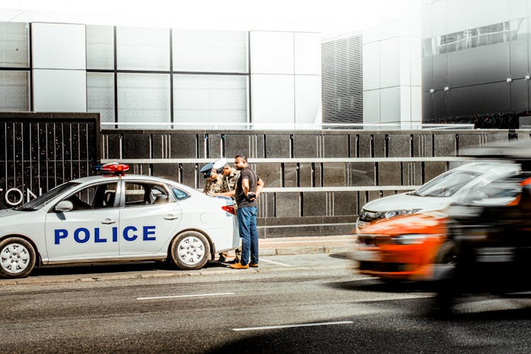 Driver Standing With Police Officers By Police Car