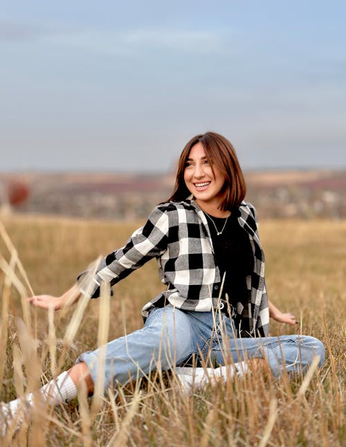 Smiling Woman Sitting in Shirt on Grassland